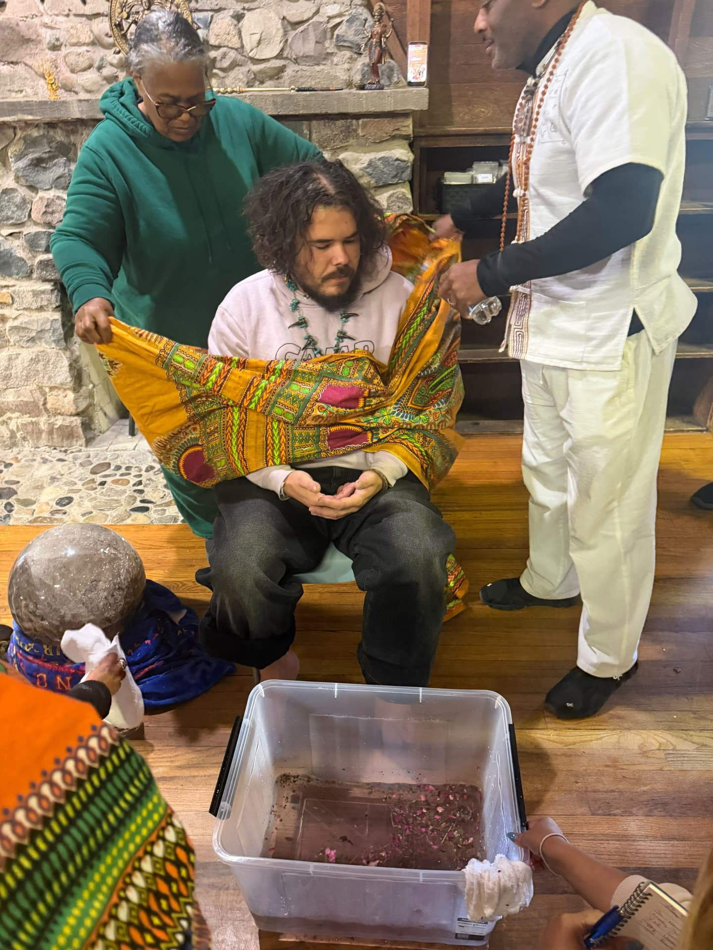 A participant rises from the chair as facilitators stand ready with the cloth
